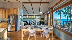 Une cuisine moderne avec des meubles en bois, un réfrigérateur en acier inoxydable et un coin repas comprenant une table et des chaises en bois.