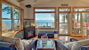 Un salon chaleureux avec de grandes fenêtres donnant sur un paysage magnifique, une cheminée et des fauteuils confortables.