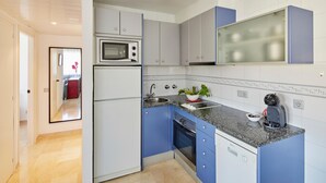 Una cocina moderna con armarios grises, microondas integrado, cafetera y fregadero.