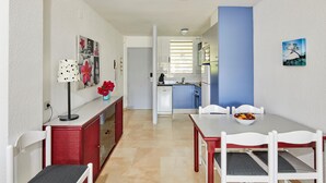 A dining area with a white table and chairs, a red cabinet, and a vase of flowers.