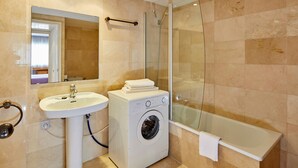 A bathroom with a sink, washing machine, and bathtub.