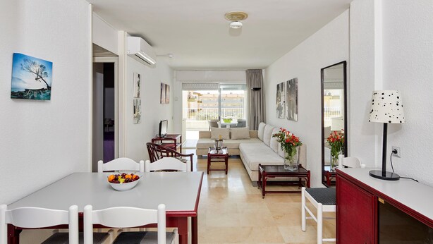 A modern living room with a dining area, a sofa set, and a small table with a bowl of fruit.