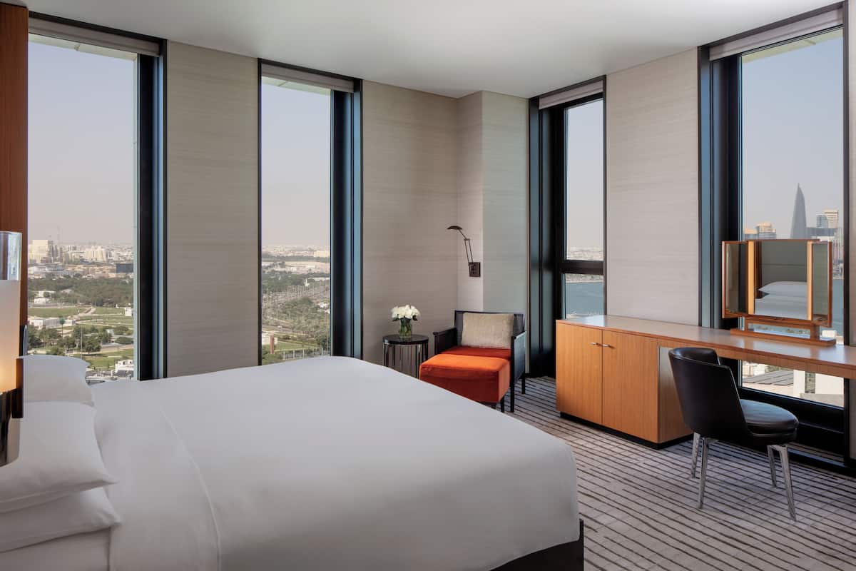 Ein modernes Hotelzimmer mit einem großen Bett, einem Schreibtisch und Blick auf die Stadt.