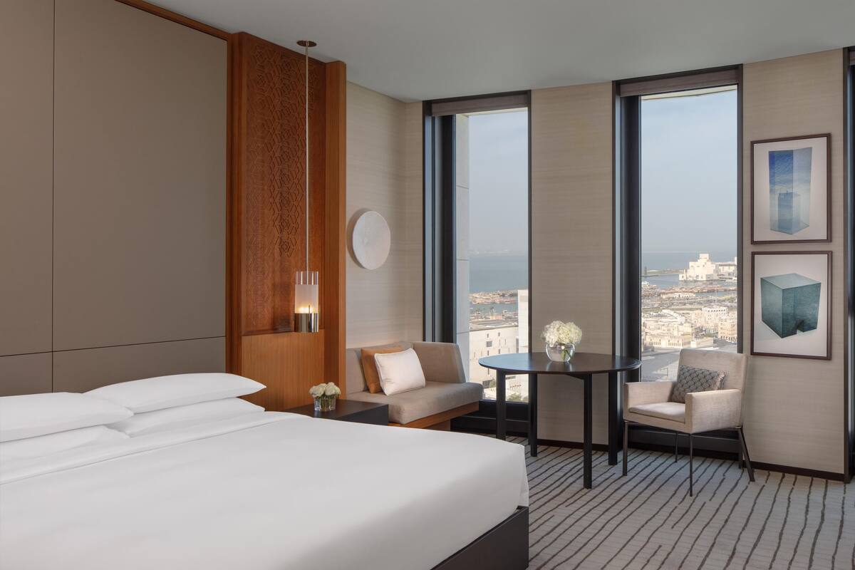 Ein Hotelzimmer mit einem großen Bett, einer Sitzecke mit Tisch und Blick auf die Stadt.