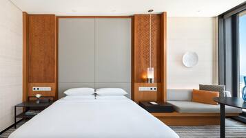 Una habitación de hotel moderna con una cama grande, un sofá, una mesita y una mesita de noche.