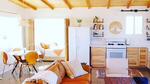 Un salon chaleureux avec un canapé en cuir, une table à manger et un coin cuisine doté de meubles en bois et d’une cuisinière.