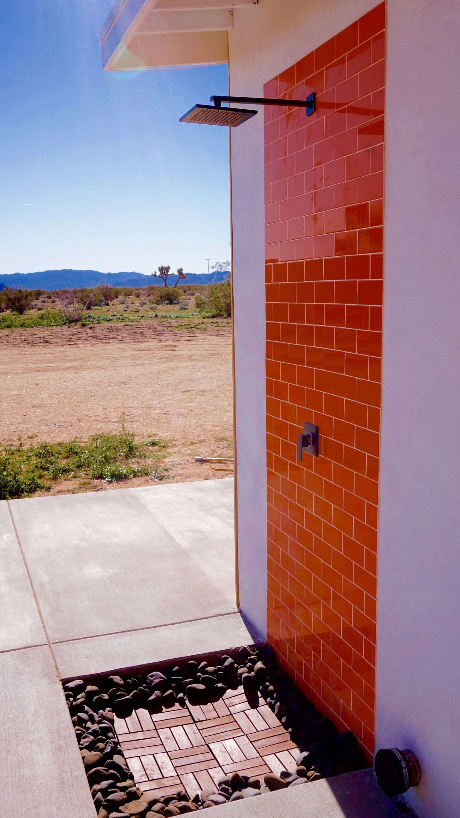 Un edificio moderno con fachada de ladrillo rojo, patio de hormigón y una vista despejada de un paisaje natural al fondo.