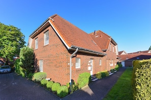 Ein zweigeschossiges Ziegelhaus mit geneigtem Dach, befestigter Auffahrt und gepflegtem Rasen.