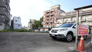 A parking area with a white car, a sign indicating a 52 traveler's home, and a red traffic cone. - 52Travelers Home (Hualien City)
