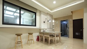 A modern kitchen with a large window, a dining table with chairs, and a built-in oven. - 52Travelers Home (Hualien City)
