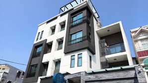 A modern multi-story building with a mix of balconies and windows, a garage entrance, and a small outdoor seating area. - 52Travelers Home (Hualien City)