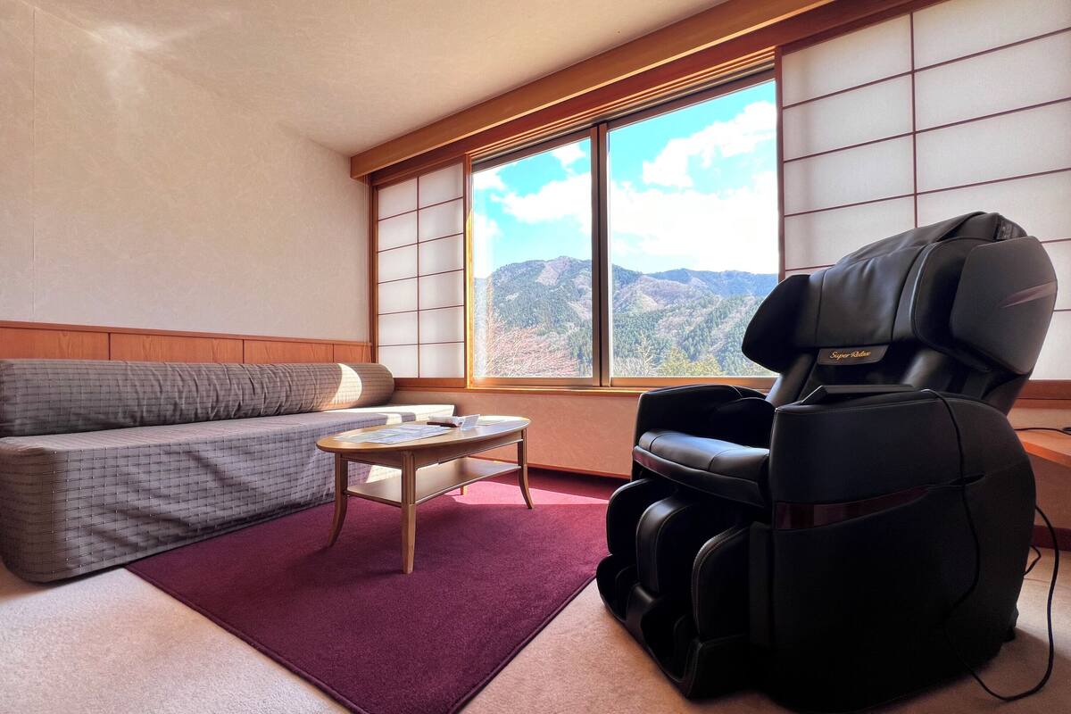 A room with a sofa, massage chair, and a table with papers.