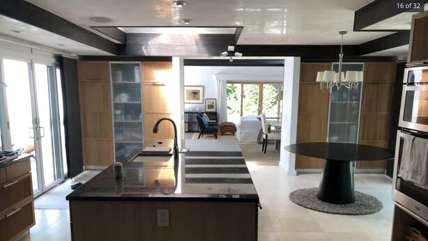Una cucina moderna con isola centrale, un'area pranzo con tavolo rotondo e vista sul soggiorno.
