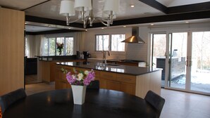 Una cucina moderna con isola centrale, ampie finestre e zona pranzo con tavolo e sedie.