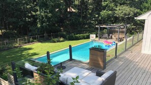 Una terrazza in legno con piscina, mobili da esterno e un pergolato.