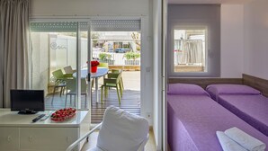 A hotel room with a bed, a desk with a computer, a chair, and a view of the outside balcony. - APARTMENT 7 ADULTS POOL VIEW (L'Estartit)