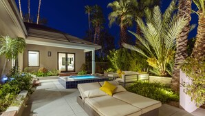 Un espace de vie extérieur moderne, doté d’une piscine, de sièges confortables et d’un aménagement paysager luxuriant.