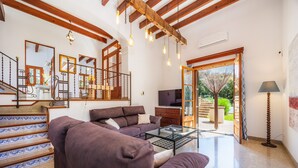 A spacious living area with a staircase, a sofa, a coffee table, and a television.