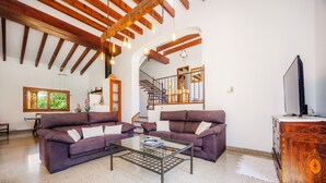 A spacious living room with two sofas, a coffee table, and a TV on a wooden cabinet.