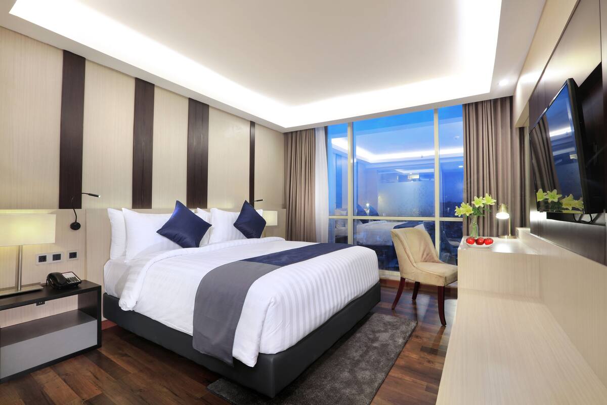 Een moderne hotelkamer met een groot bed, een bureau, een stoel en een televisie.