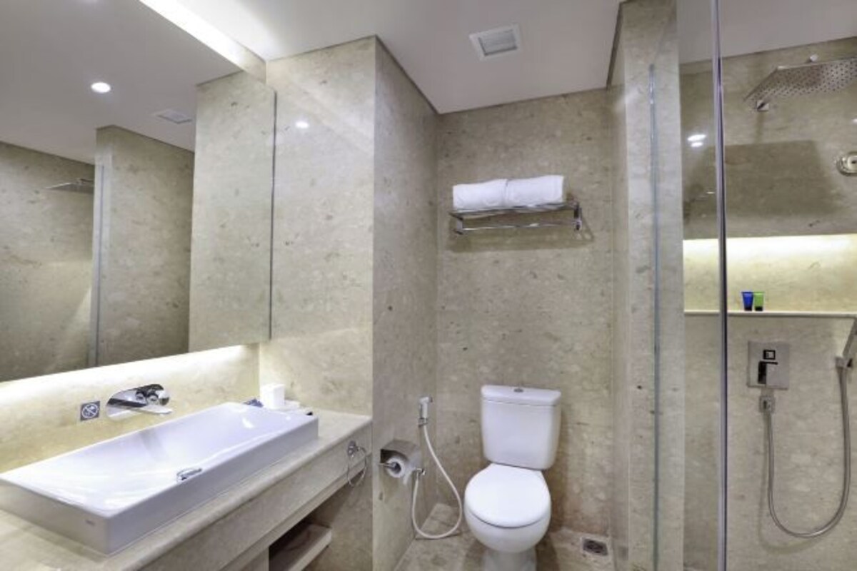 A modern bathroom with a large mirror, a sink, a toilet, and a shower.