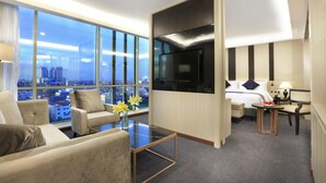 Een moderne hotelkamer met een groot raam, een bed, een bank, een salontafel en een televisie.