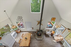 A spacious loft with a high ceiling, a central fireplace, and a large window providing a view of the outdoors.