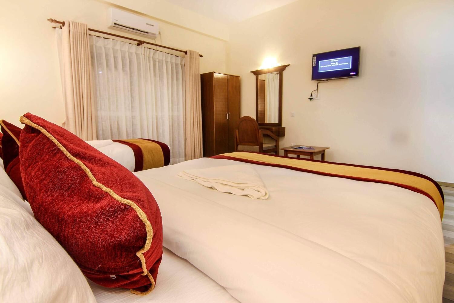 Una habitación de hotel con una cama grande, un televisor montado en la pared y una mesita pequeña.