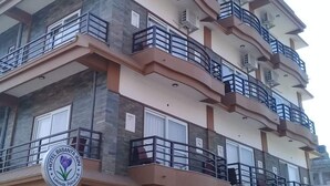 Un hotel de varios pisos con balcones, un logotipo y una entrada protegida.