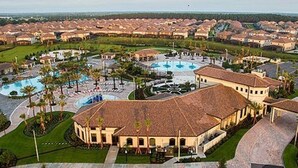 A resort with multiple buildings, a central pool area, and surrounding greenery. - Voluminous * 5 Bd Pool/Spa Home in Champions Gate (Davenport)