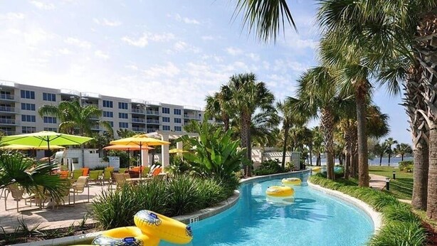 A swimming pool with multiple yellow inflatable rings, surrounded by palm trees and lounge chairs. - Voluminous * 5 Bd Pool/Spa Home in Champions Gate (Davenport)
