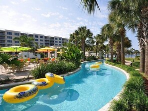 Una piscina con varios flotadores amarillos, rodeada de palmeras y sillones de descanso.