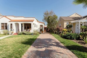 Una calle residencial con dos casas, un sendero pavimentado y jardines bien cuidados.