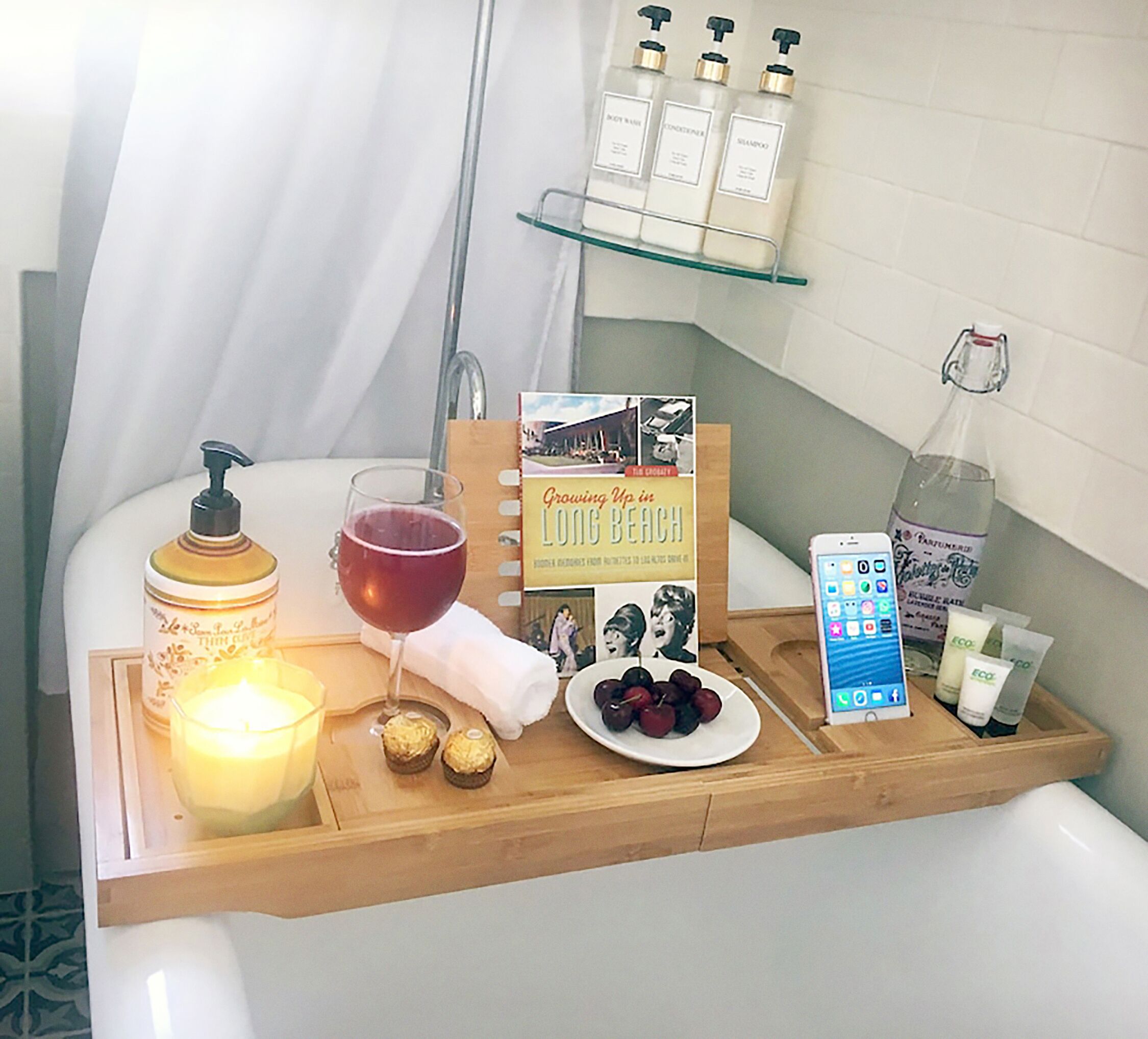 Un tocador de baño con artículos de aseo, una vela, un libro y una bandeja de fruta.