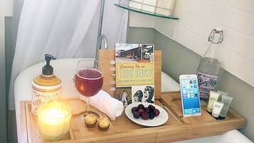 Un tocador de baño con artículos de aseo, una vela, un libro y una bandeja de fruta.