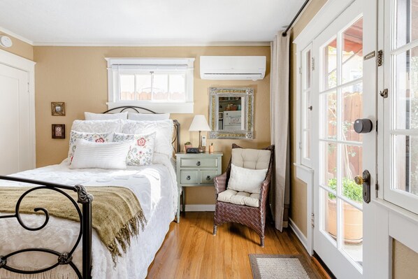 Une chambre à coucher comprenant un lit, une table de chevet, une chaise et une porte donnant sur l’extérieur.