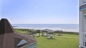 A coastal house with a grassy lawn, a gazebo, and a view of the ocean. - NEW LISTING Day Break at SeaScape #2219: A Place to Rest, Relax, and Rejuvenate! (Galveston)