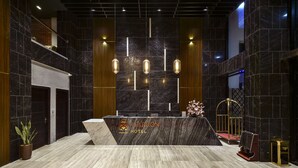A reception area with a marble counter, hanging pendant lights, and a potted plant. - The Marron Hotel (Sam Son)
