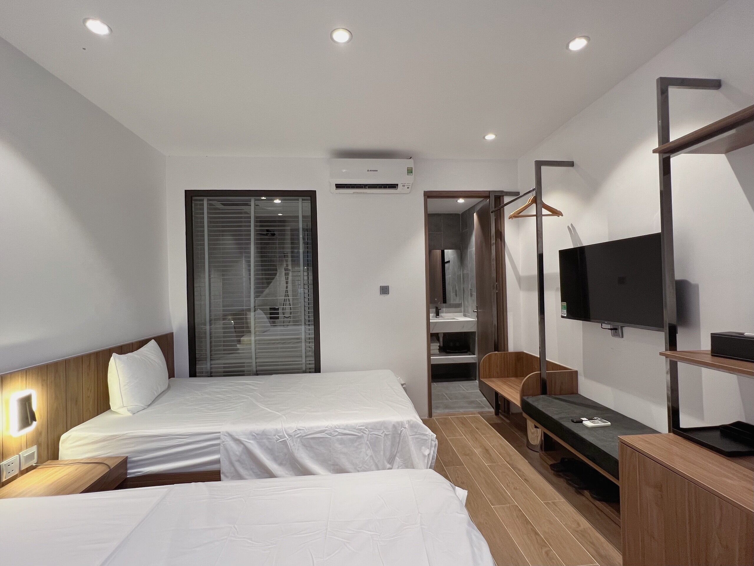 A hotel room with two beds, a TV, a desk, and a walk-in closet.