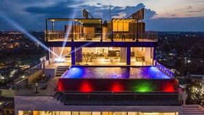A multi-level rooftop with a pool, outdoor seating, and a view of the cityscape. - The Marron Hotel (Sam Son)