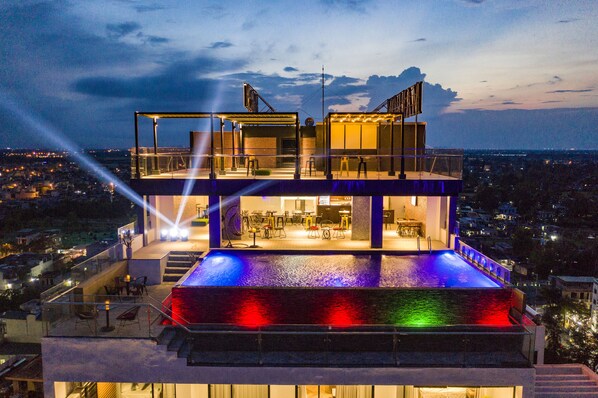 A multi-level rooftop with a pool, outdoor seating, and a view of the cityscape. - The Marron Hotel (Sam Son)
