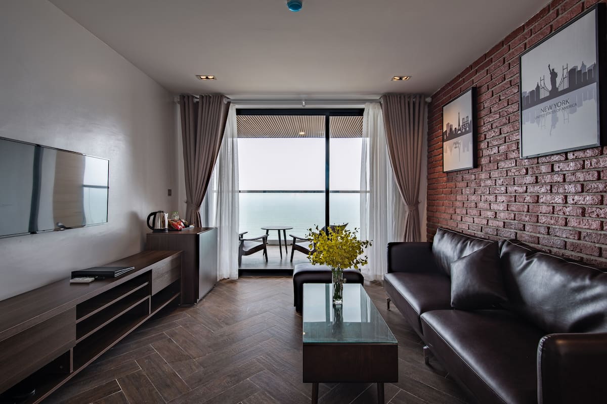 A modern living room with a glass coffee table, leather sofa, and a TV mounted on the wall.
