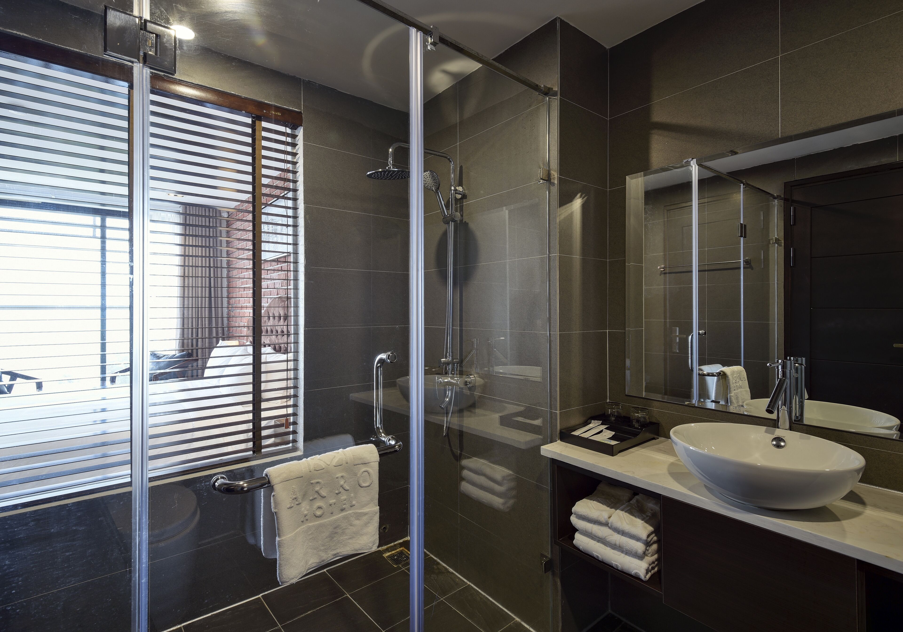 Ein modernes Badezimmer mit einer gläsernen Duschkabine, einem großzügigen Waschbecken und einem Spiegel.