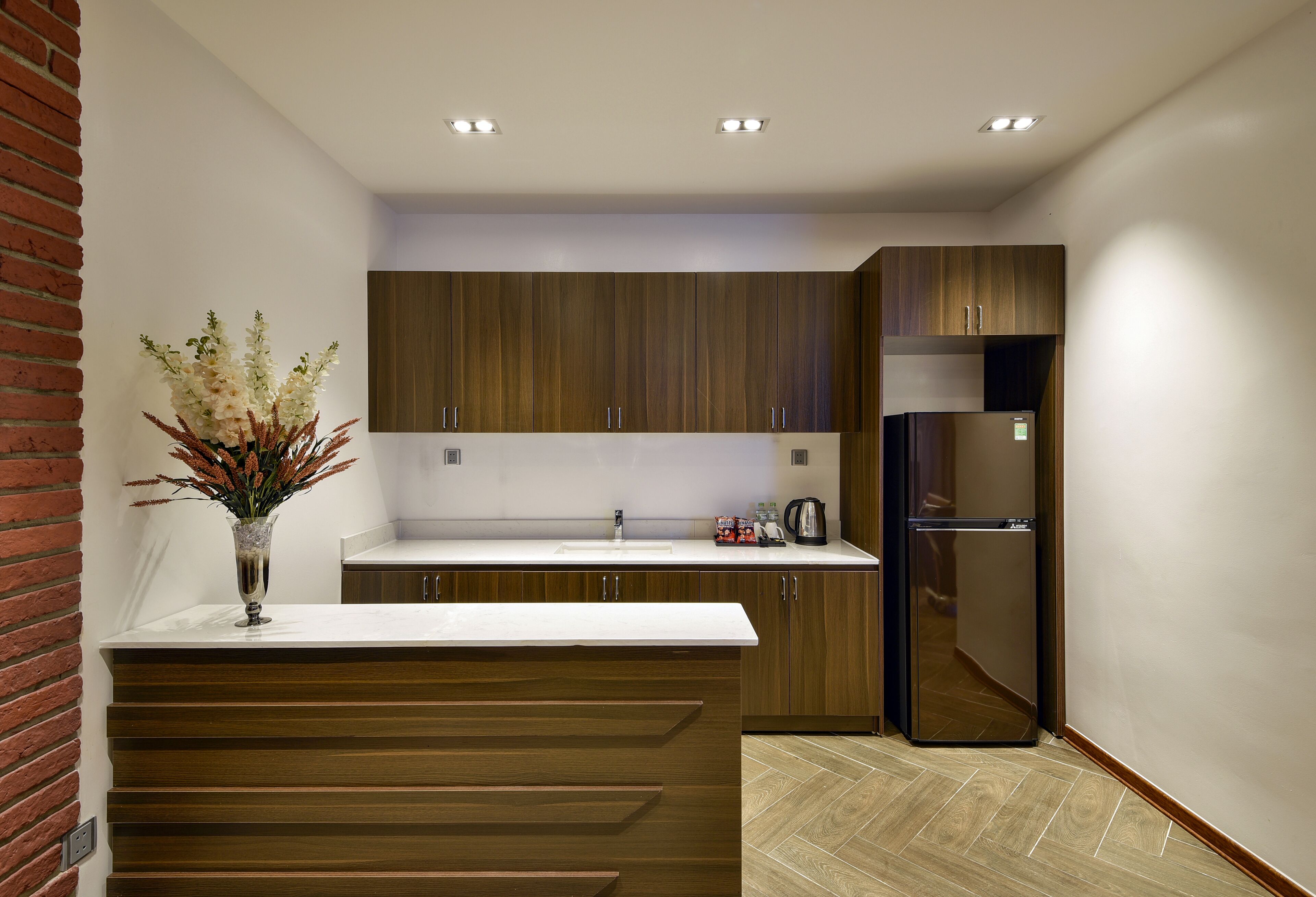 A modern kitchen with wooden cabinets, a white countertop, and a built-in refrigerator.
