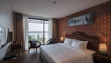 Una habitación de hotel con una cama grande, televisión, una silla y vistas al exterior.