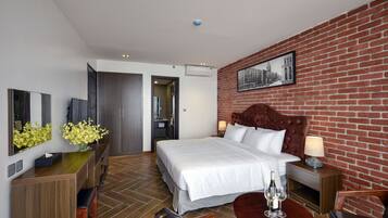 Una habitación de hotel con una cama grande, un escritorio de madera, una mesa de comedor y una pared de ladrillo.