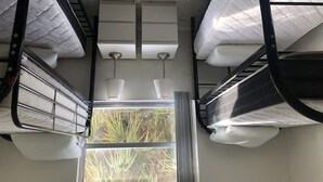 A bunk bed room with a window, metal railings, and a ceiling fan.