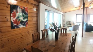 Ett matbord i trä med stolar, en vas med växter och en färgstark, abstrakt tavla på väggen.