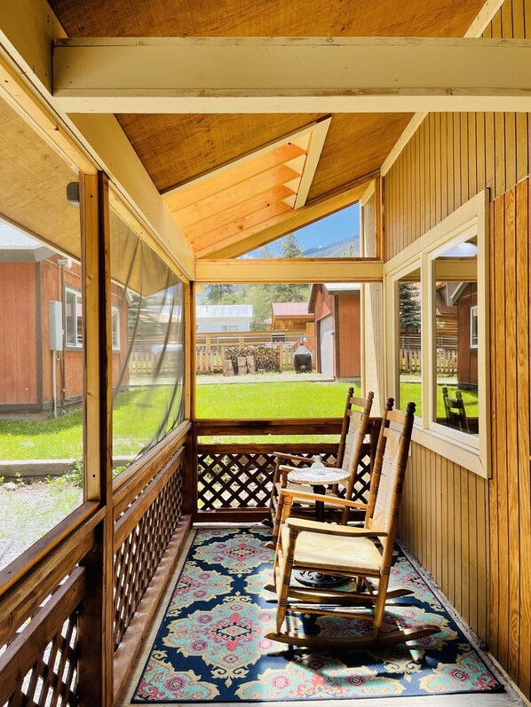 A covered porch with wooden chairs and a patterned rug. - Gowdy Suite 1, King Bed, Hot Tub, Screened Porch, Free wifi. (Lake City)