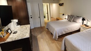 A hotel room with two beds, a wooden floor, a kitchen area with a marble countertop, and a small wooden nightstand. - 224-A Studio/Main St/Town Lift/Pool/Hot Tub/Parking  (Park City)